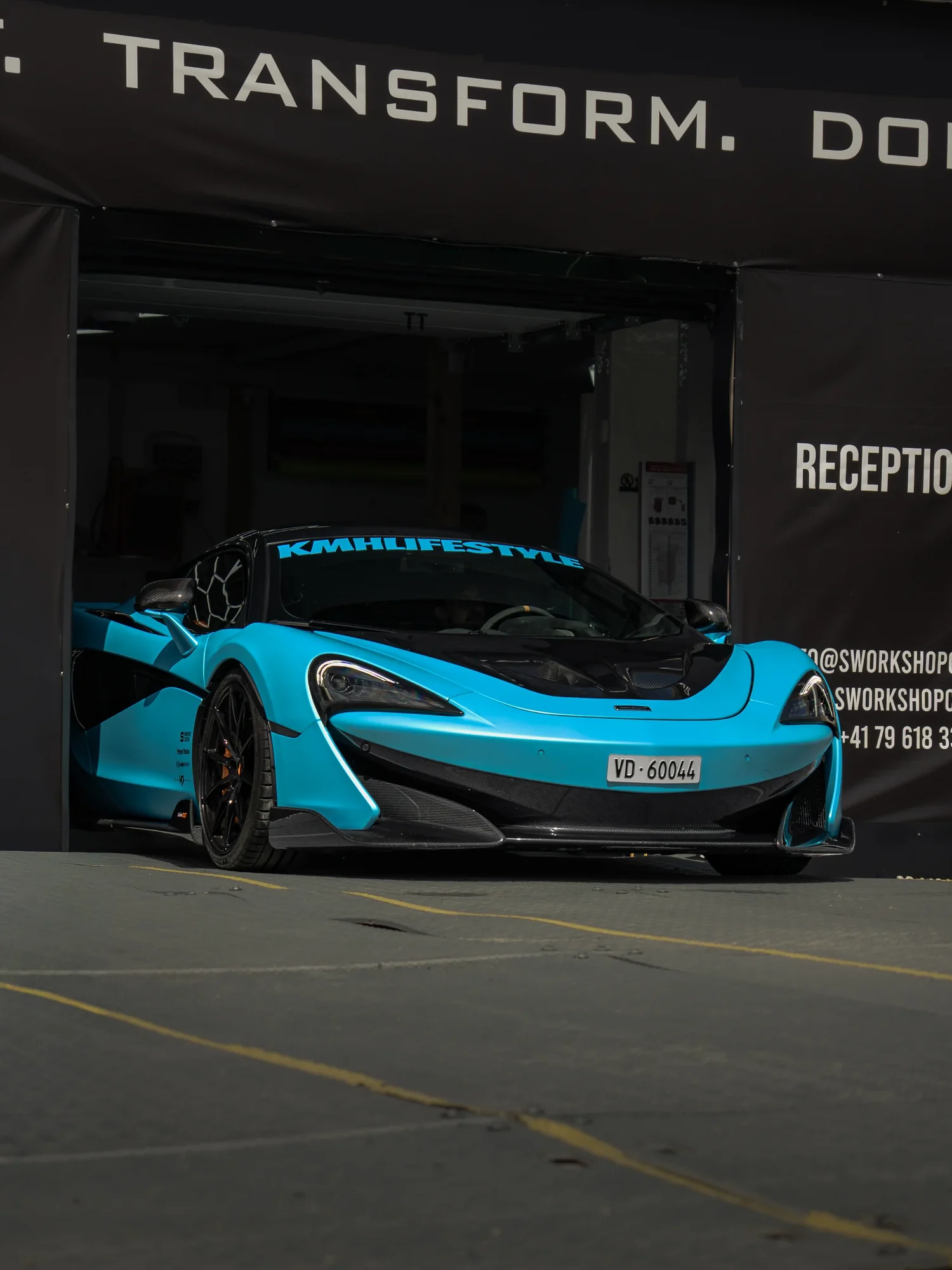 McLaren 600LT en full covering bleu devant l'atelier